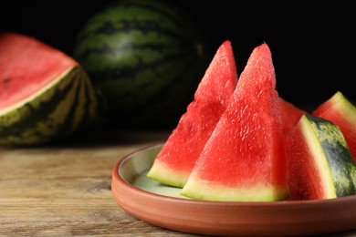 Plate with slices of juicy watermelon on wooden table, closeup. Space for text