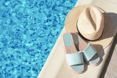 Photo of Stylish slippers and straw hat at poolside on sunny day, space for text. Beach accessories