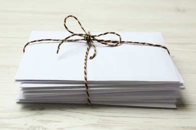 Stack of letters tied with string on white wooden table, closeup