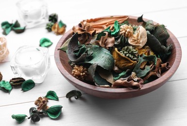 Photo of Aromatic potpourri of dried flowers in bowl on white wooden table