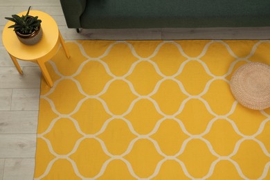 Yellow carpet with geometric pattern on wooden floor in living room, above view