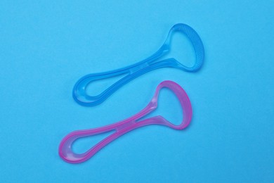 Tongue cleaners on blue background, flat lay