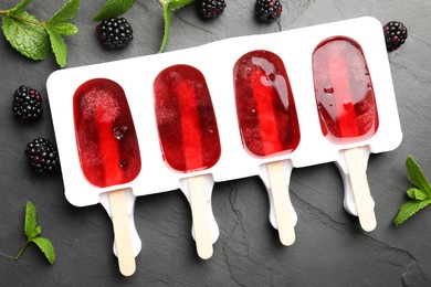 Tasty berry ice pops in mold on grey table, flat lay. Fruit popsicle