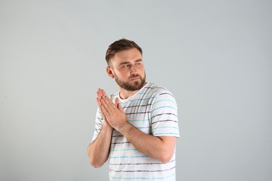 Greedy young man rubbing hands on light grey background