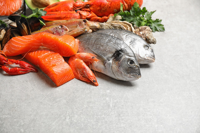 Fresh raw fish and different seafood on light grey table