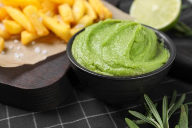 French fries, lime, rosemary and avocado dip on serving board, closeup