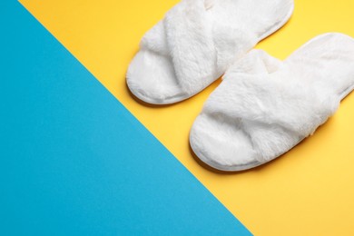 Pair of soft slippers on color background. Space for text