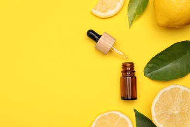 Bottle of citrus essential oil, pipette and fresh lemons on yellow background, flat lay. Space for text