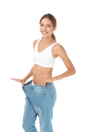 Young slim woman in old big jeans showing her diet results on white background