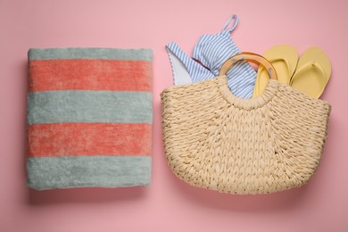 Beach bag with swimsuit, flip flops and towel on pink background, flat lay