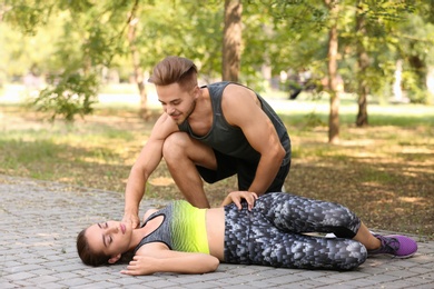 Man checking pulse of unconscious woman outdoors