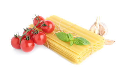 Uncooked lasagna sheets with cherry tomatoes, garlic and basil isolated on white