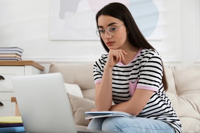 Young woman watching webinar on sofa at home