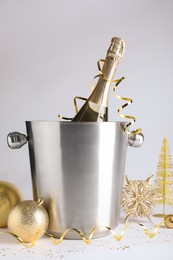 Happy New Year! Bottle of sparkling wine in bucket and festive decor on white background