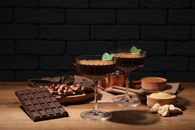 Dessert bowls of delicious hot chocolate and ingredients on wooden table