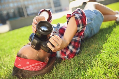 Young photographer taking picture with professional camera on green grass