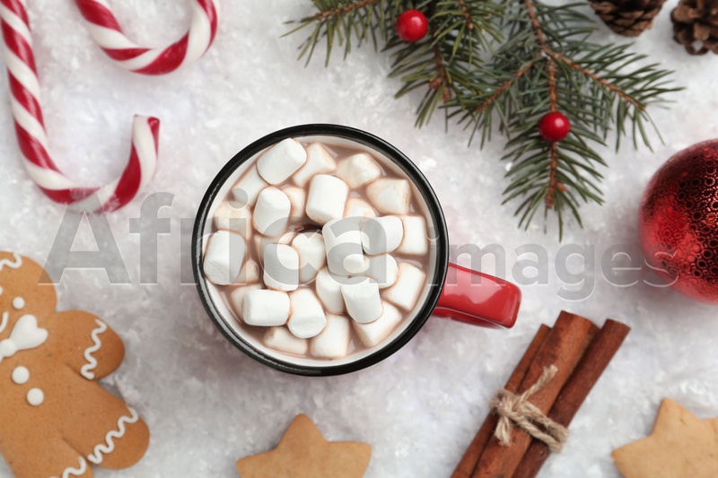 Hot drink with marshmallows, sweets and festive decor on snow, flat lay
