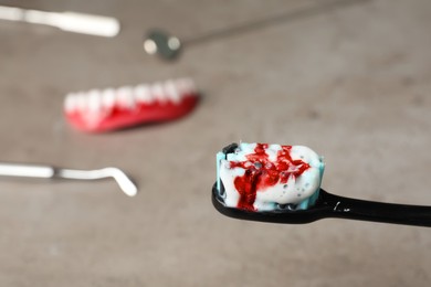 Photo of Toothbrush with paste and blood on blurred background, space for text. Gum inflammation