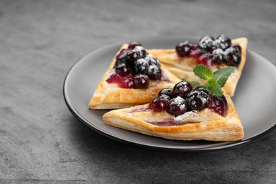 Photo of Fresh tasty puff pastry with sugar powder, jam, sweet berries and mint on grey table, closeup