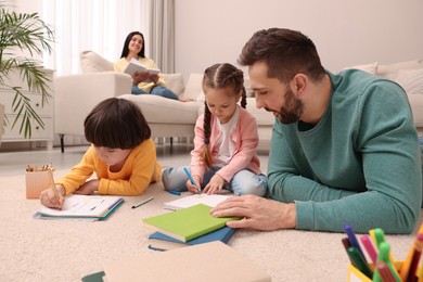 Father playing with his children while mother reading book on sofa in living room