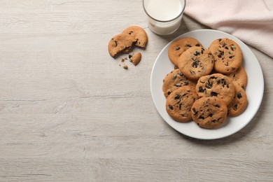 Delicious chocolate chip cookies and glass of milk on white wooden table. Space for text
