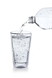 Pouring soda water from bottle into glass on white background