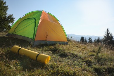 Photo of Sleeping mat near camping tent in mountains. Tourism equipment