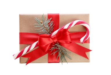 Christmas gift box decorated with red bow, candy cane and fir tree branch on white background, top view