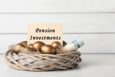 Many golden eggs, money and card with phrase Pension Investments on table near white wooden wall