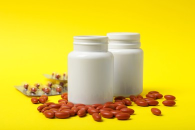 Bottles with pills on yellow background. Anemia treatment
