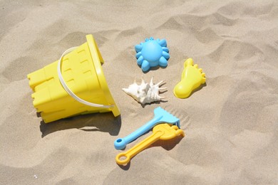 Bright plastic bucket and rakes on sand. Beach toys
