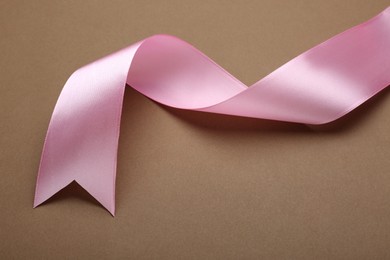 Beautiful pink ribbon on brown background, closeup. Space for text