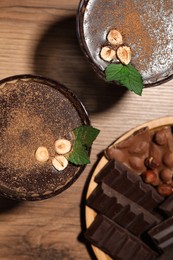 Photo of Dessert bowls of delicious hot chocolate with hazelnuts and fresh mint on wooden table, flat lay
