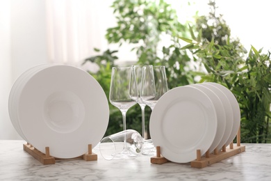 Set of clean dishware and wineglasses on white table against blurred background