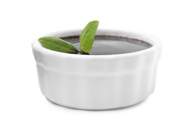 Photo of Balsamic glaze with basil leaves in bowl isolated on white
