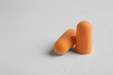 Pair of orange ear plugs on grey background, closeup. Space for text