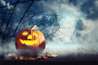 Image of Spooky Jack O Lantern pumpkin surrounded by mystical mist under full moon on Halloween. Space for text