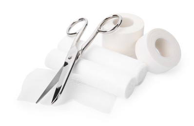 Medical bandage rolls, sticking plaster and scissors on white background