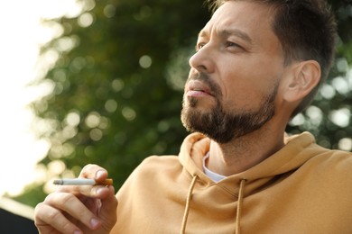 Photo of Handsome mature man smoking cigarette outdoors on sunny day