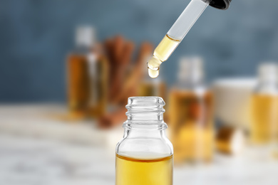Little bottle with essential oil and dropper against blurred background 