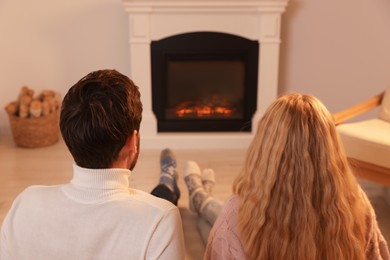 Photo of Lovely couple spending time together near fireplace at home, back view