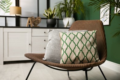 Comfortable wicker armchair with soft pillows in modern room. Interior design