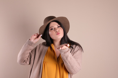 Beautiful overweight woman posing on beige background. Plus size model
