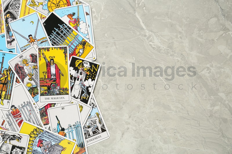 Tarot cards on light grey marble table, top view. Space for text