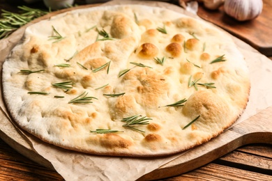 Focaccia bread with rosemary on wooden table, closeup