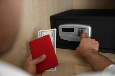 Man opening black steel safe with electronic lock at hotel, closeup
