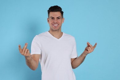 Handsome man snapping fingers on light blue background