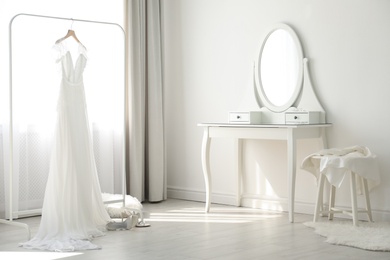 Beautiful wedding dress hanging on clothing rack in room