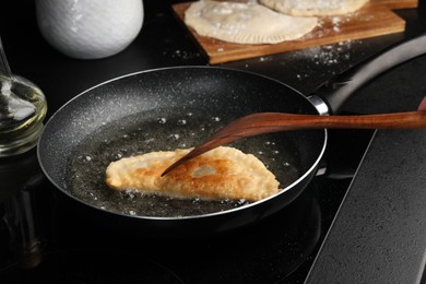 Photo of Cooking chebureki with tasty filling in frying pan