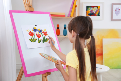 Cute little child painting during lesson in room
